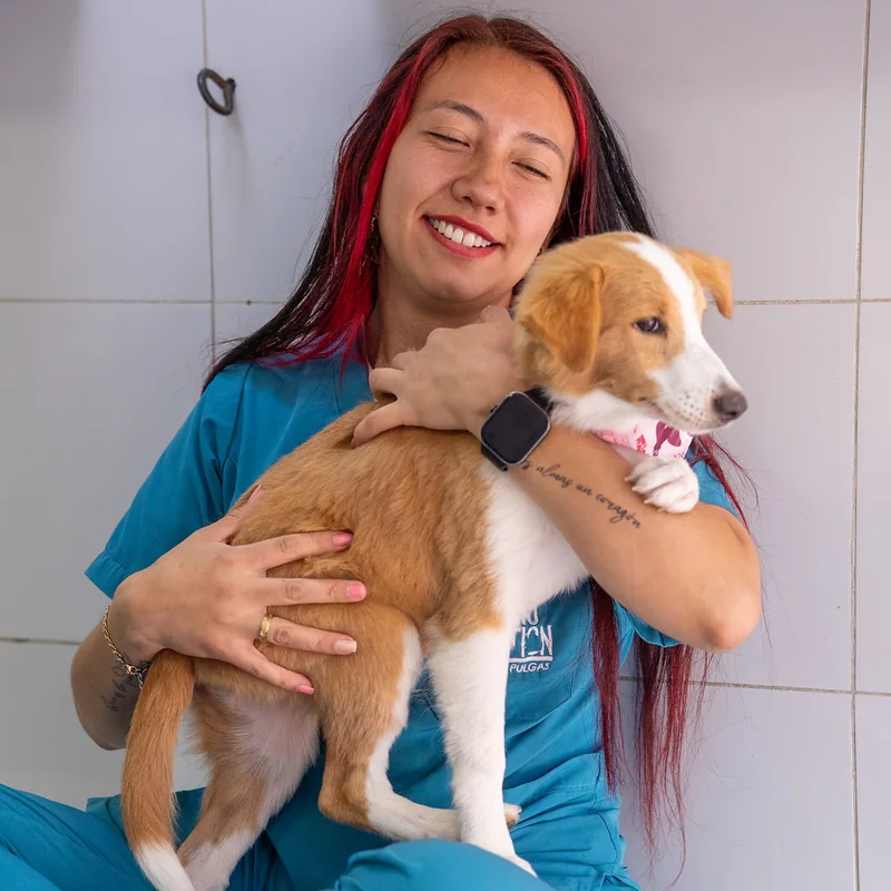 Groomer de Guau Station sonriendo con un cachorro en brazos, lista para atender tu cita